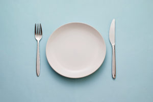 بشقاب غذای سفید با چنگال و چاقو در زمینه آبی